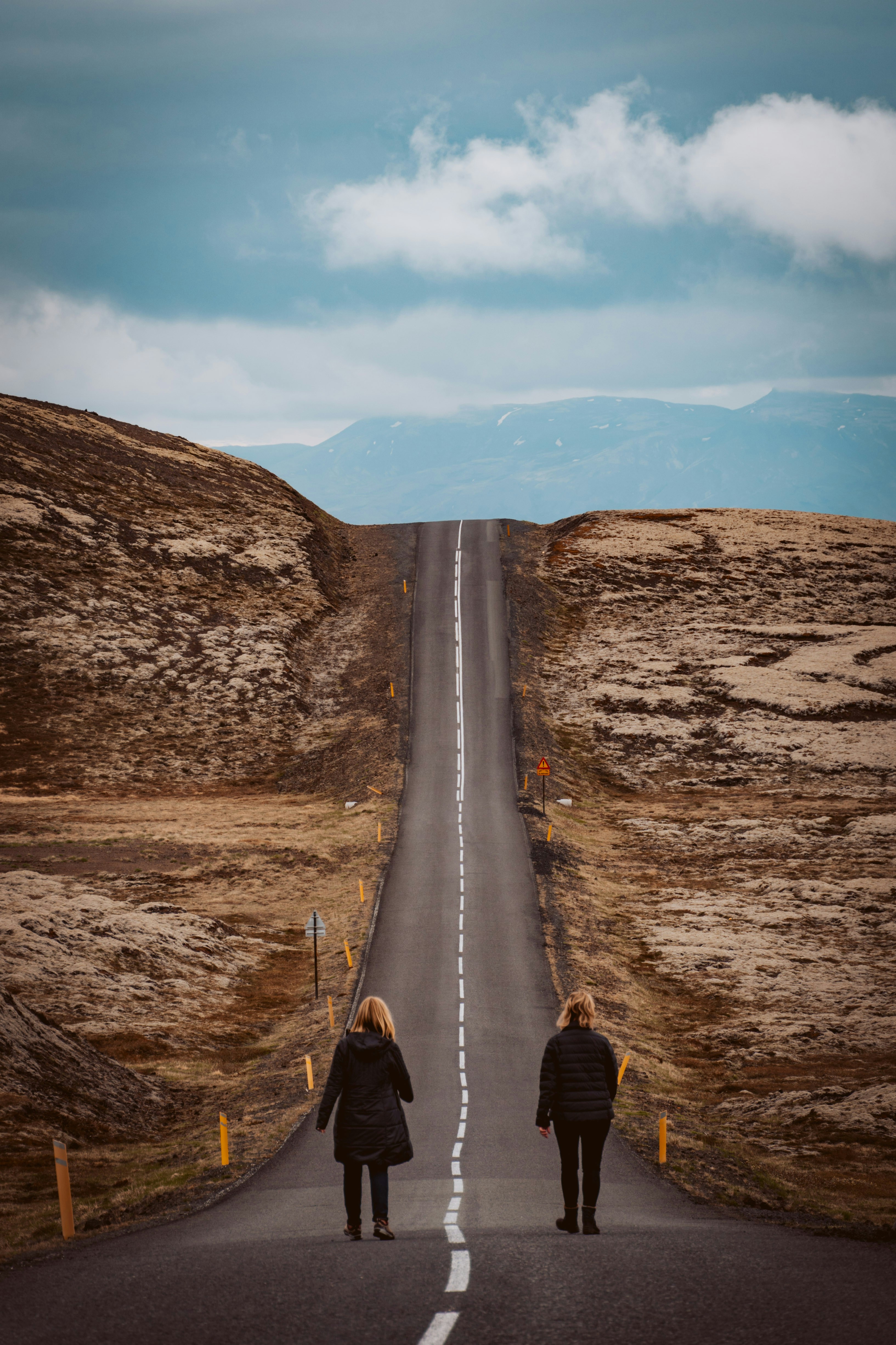 Two people walking a long open road